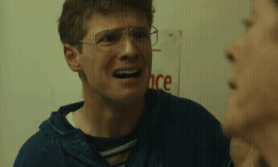 Man With Glasses Talking To Another Man In Front Of Sign Saying Ance GIF