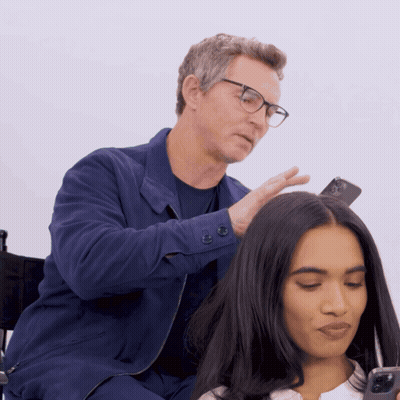 Man With Glasses Touching Woman's Hair Holding Cell Phone GIF