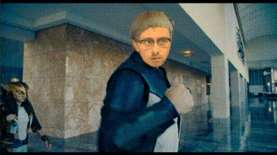 Man With Glasses Walking Down Hallway With Masked Woman Behind GIF
