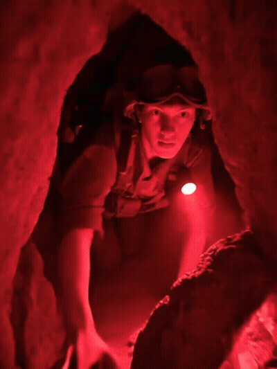 Man With Goggles And Helmet Crawling Through Cave GIF