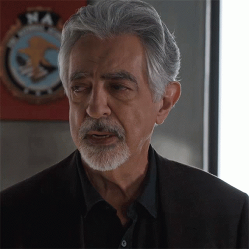 Man With Gray Hair And Beard In Front Of NA Logo GIF