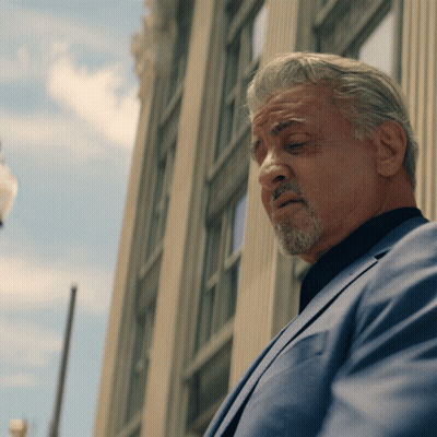 Man With Gray Hair And Beard Stands In Front Of Building GIF