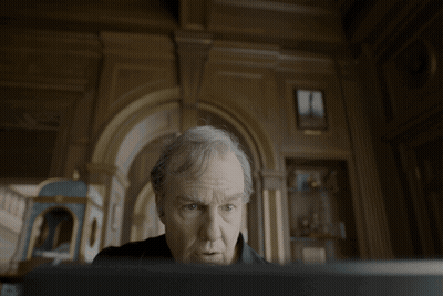 Man With Gray Hair Looking At Screen In Dark Room GIF
