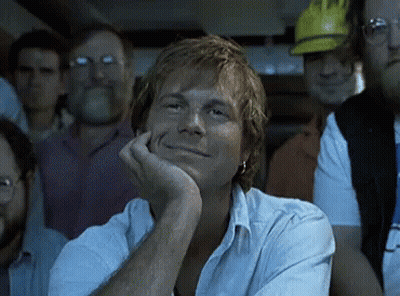 Man With Hand On Chin Smiling In Crowd GIF