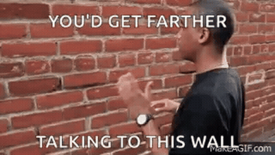 Man With Hands Up In Front Of Brick Wall GIF