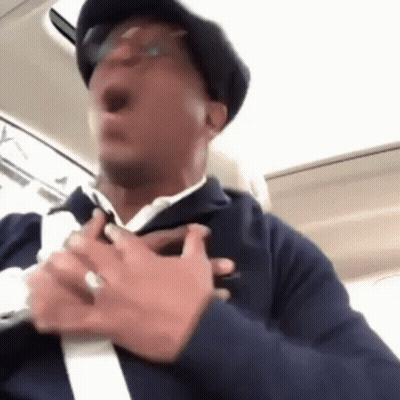Man With Hat And Glasses Holding Chest In Car GIF