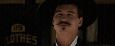 Man With Hat And Mustache Waving In Front Of Hes Sign GIF
