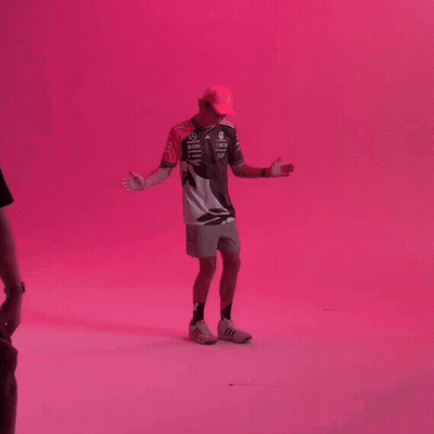 Man With Hat Arms Outstretched Pink Wall GIF