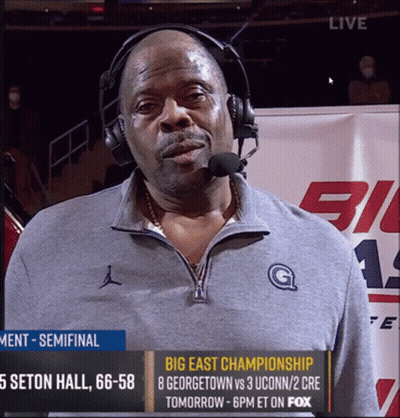 Man With Headphones In Front Of Big East Banner GIF