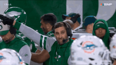 Man With Headphones In Front Of Football Players GIF