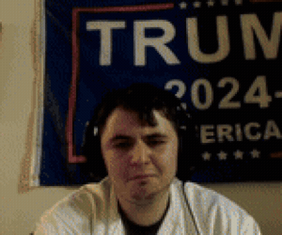 Man With Headphones In Front Of Trump Sign GIF