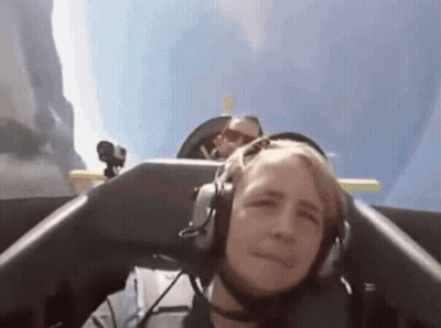 Man With Headphones On Plane, Another Man Behind GIF