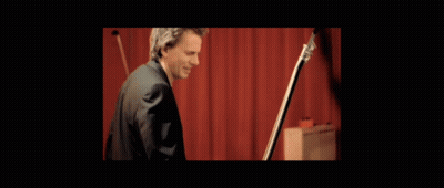 Man With Headphones Playing Guitar At Red Wall GIF