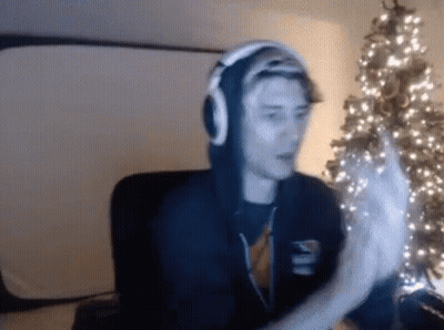 Man With Headphones Sitting By Christmas Tree GIF