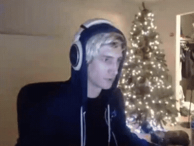 Man With Headphones Sitting By Christmas Tree GIF
