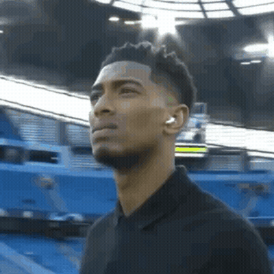 Man With Headphones Standing In Front Of Stadium GIF