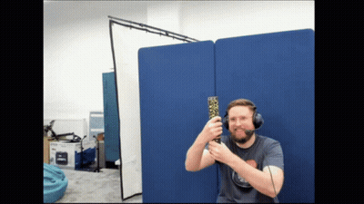 Man With Headset Holding Remote in Front of Blue Wall