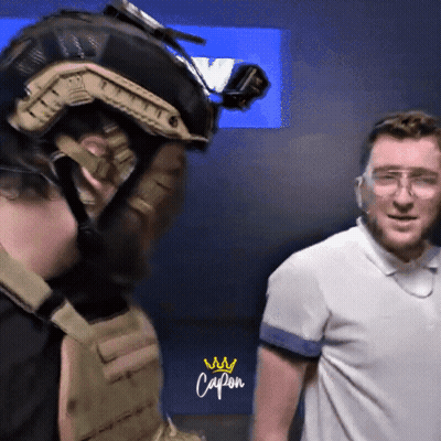 Man With Helmet And Goggles Next To Man In Capon Shirt GIF