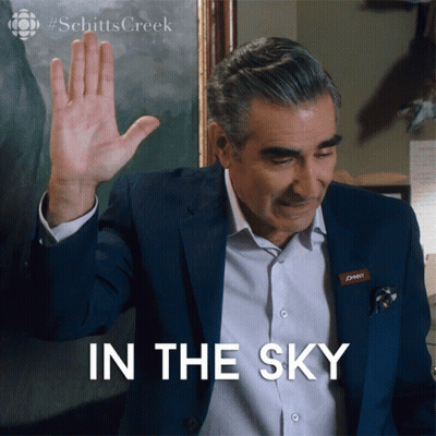 Man With Johnny Nametag Waving Hand In Front Of In The Sky Sign GIF