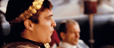 Man With Laurel Wreath Sitting Next To Man GIF