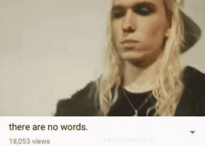 Man With Long Blonde Hair In Black Hat And Shirt GIF