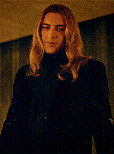 Man With Long Blonde Hair In Black Turtleneck And Jacket GIF