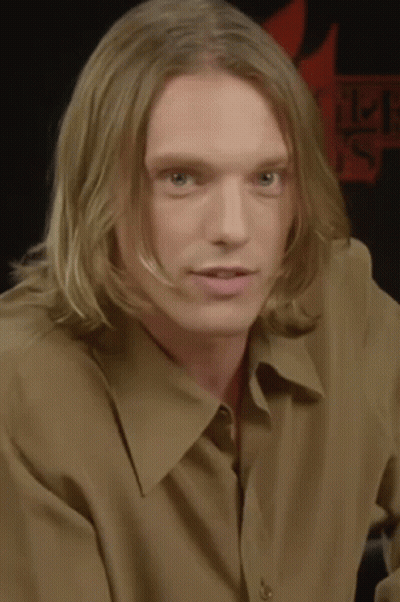 Man With Long Blonde Hair In Brown Shirt GIF