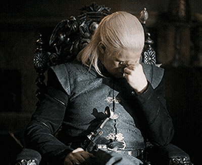 Man With Long Blonde Hair Sitting In Chair Hand On Face GIF