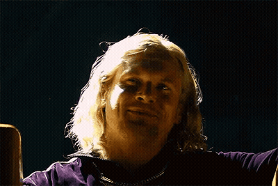 Man With Long Blonde Hair Sitting In Dark Room GIF