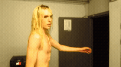 Man With Long Blonde Hair Standing In Room GIF
