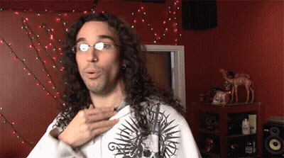 Man With Long Curly Hair And Glasses In Skull Shirt GIF