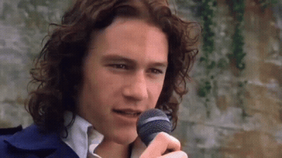 Man With Long Curly Hair Singing Into Microphone GIF