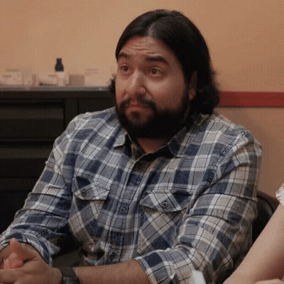 Man With Long Hair And Beard Looks At Camera GIF
