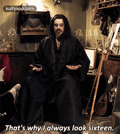 Man With Long Hair And Beard Sitting With Cane And Phone GIF