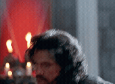 Man With Long Hair And Beard Standing In Candlelit Room GIF