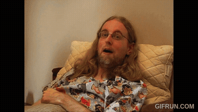 Man With Long Hair And Glasses Laying On Bed GIF