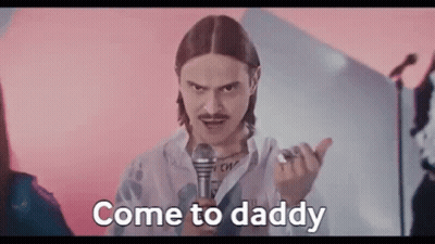 Man With Long Hair And Mustache Holding Microphone Saying Come To Daddy GIF