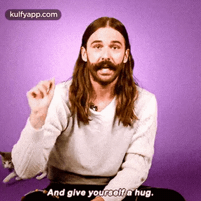 Man With Long Hair And Mustache Hugging Himself GIF