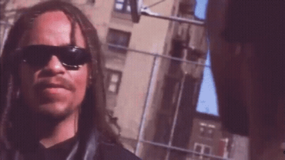 Man With Long Hair And Mustache In Sunglasses Next To Another Man GIF