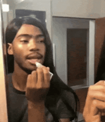Man With Long Hair Applying Lipstick In Mirror GIF