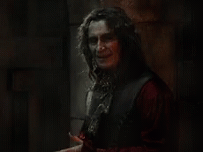 Man With Long Hair Holding Knife In Dark Room GIF
