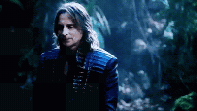 Man With Long Hair In Blue Jacket Standing In Woods GIF
