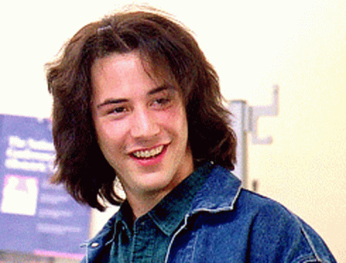 Man With Long Hair In Denim Jacket Smiles GIF