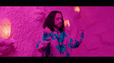 Man With Long Hair In Front Of Purple Wall GIF