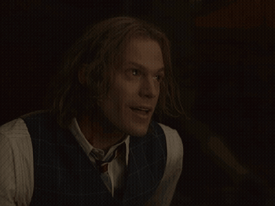 Man With Long Hair In Vest And Tie Smiles GIF