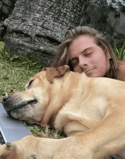 Man With Long Hair Laying Down With Dog On Lap GIF