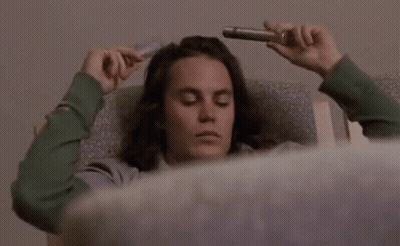 Man With Long Hair Laying In Chair Holding Pipe To Head GIF