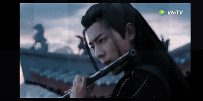 Man With Long Hair Playing Flute In Dark Room GIF