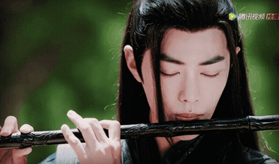 Man With Long Hair Playing Flute In Front Of Screen Saying A GIF