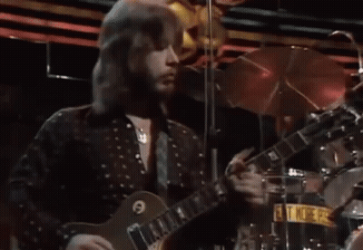 Man With Long Hair Playing Guitar On Stage GIF